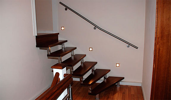 Eine zwei Holmtreppenanlage gefertigt mit Rechteckrohr aus Edelstahl poliert und Massivholzstufen. Der Edelstahlwandhandlauf ist dem Treppenverlauf angepasst.