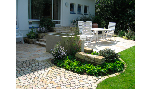 Terrasse durch Kübelpflanzen, Hochbeet und Gartenbeet in das Gesamtkonzept des Gartens integriert