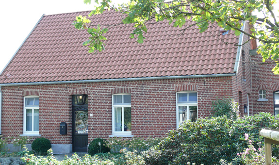 Referenzbeispiel ein ehemalig landwirtschaftlich genutztes Gebäude mit Satteldach, stilerhaltend saniert mit Hohlfalzziegeln und Holz-Windfedern