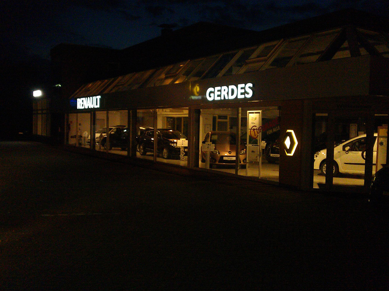 K. Gerdes GmbH - Automobile in Oldenburg - Beleuchtete Ausstellungshalle bei Dunkelheit.