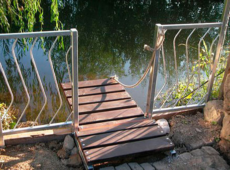 der besondere Schmuckzaun - ein Stück des Zaunes dient gleichzeitig als Steg zum Teich