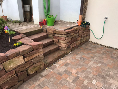 Terrasse mit Gartentreppe und Hochbeeten aus Naturstein